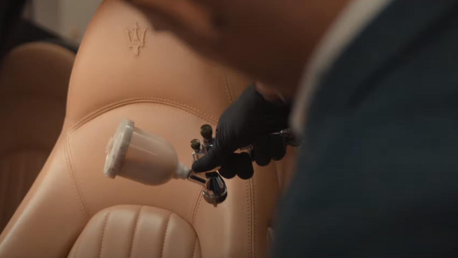 Techniker färbt die Sitzwange eines Maserati mit der Spritzpistole im Originalton nach
